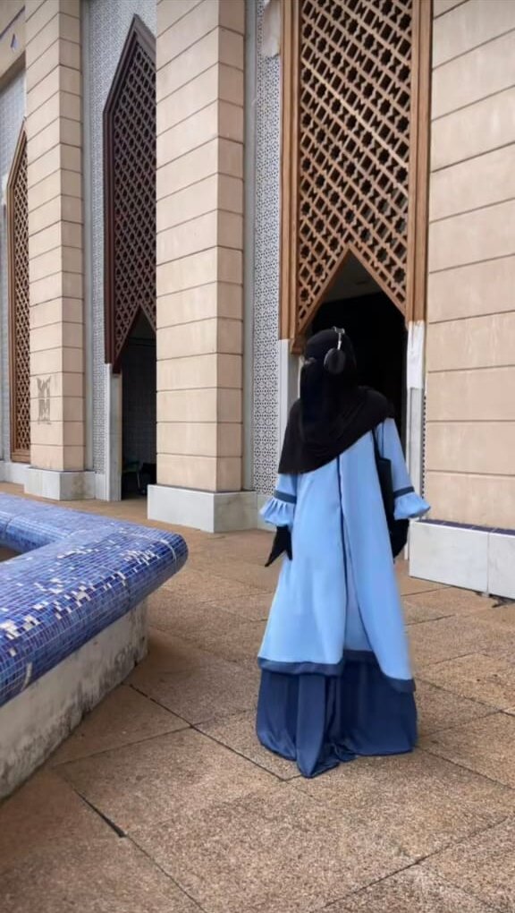 Ensemble bleu ciel porté devant une mosquée